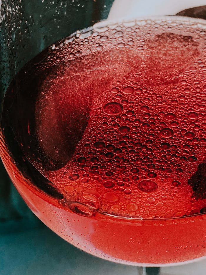From above of crystal glass of red fizzy refreshing drink placed on table
